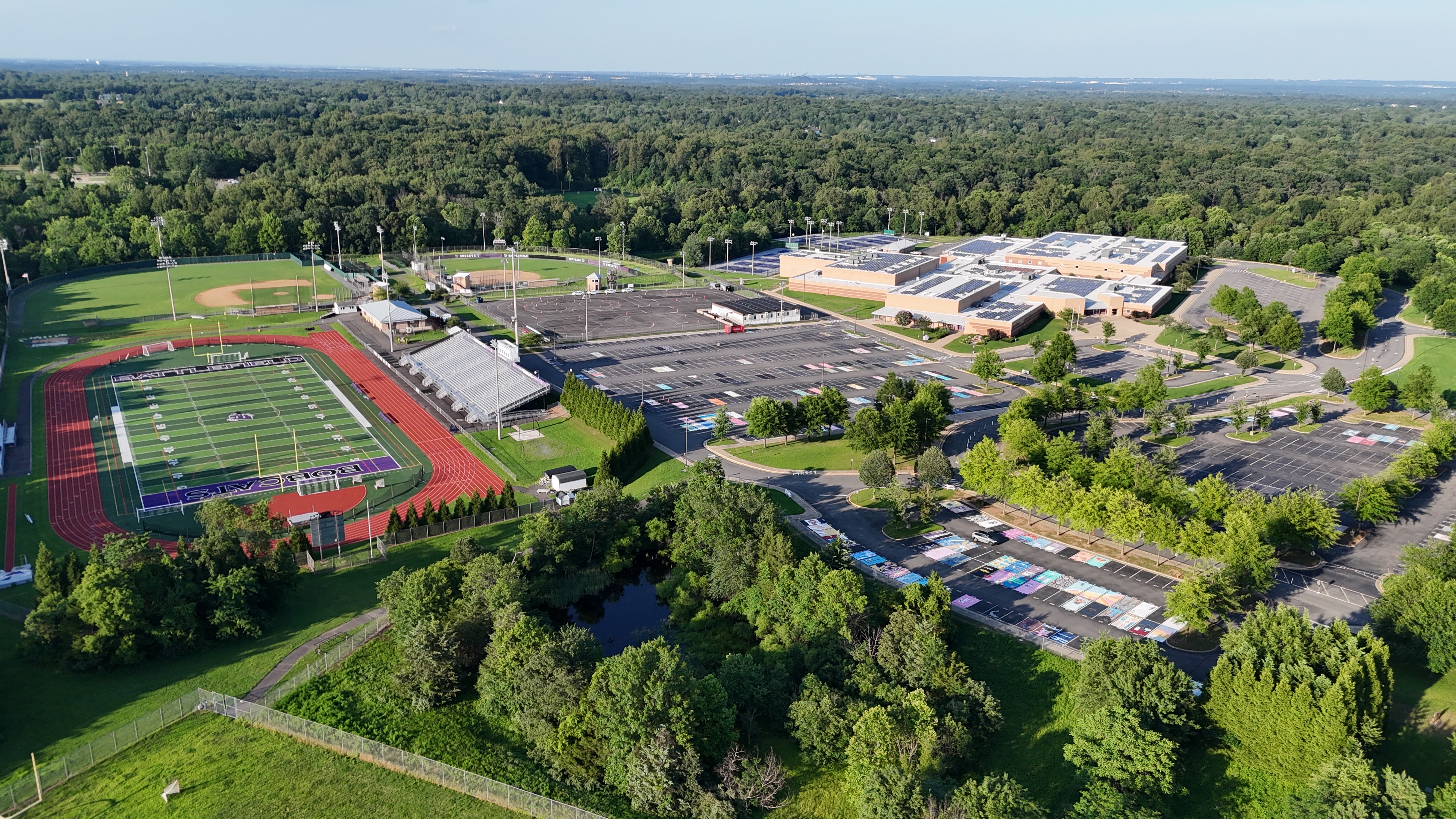 An aerial view of Battlefield High School in Haymarket, Virginia, showing the school building, football field, track, and parking lots.
