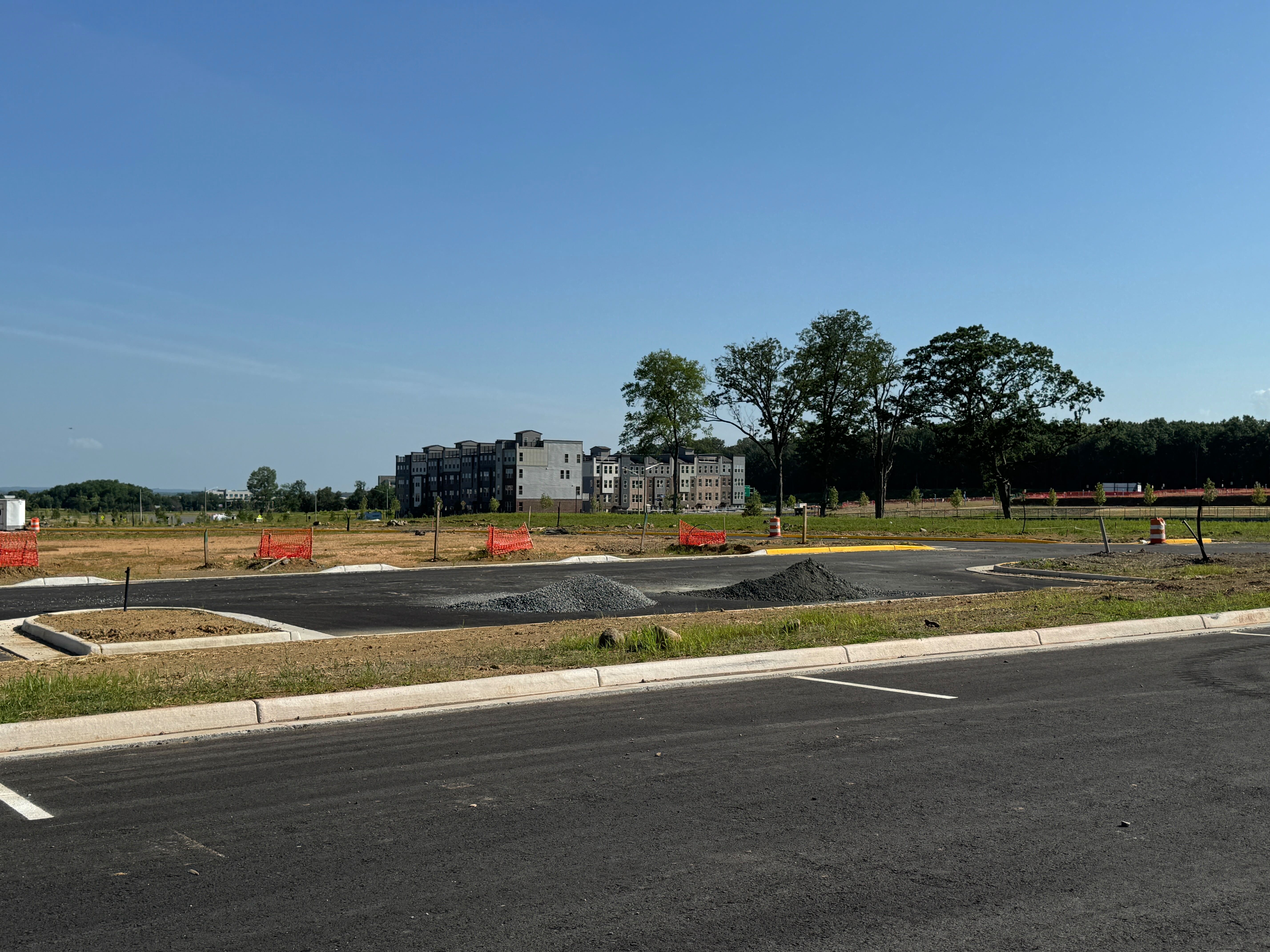 A new parking lot under construction at Innovation Town Center, with apartment buildings visible in the background.