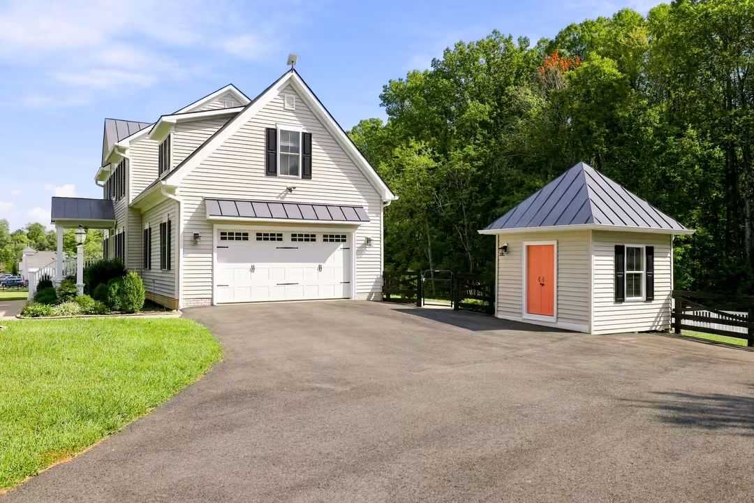 White Northern Virginia home with attached garage, paved driveway, and detached outbuilding